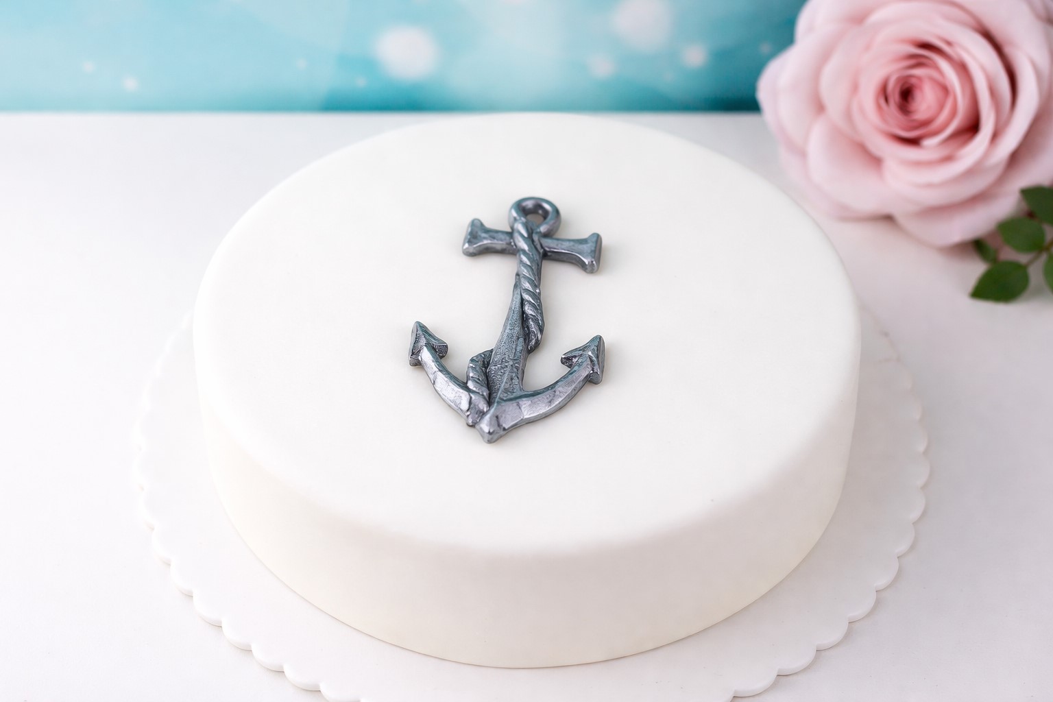 Essbarer Fondant Anker in Silber als maritime Tortendeko auf weißer Fondanttorte